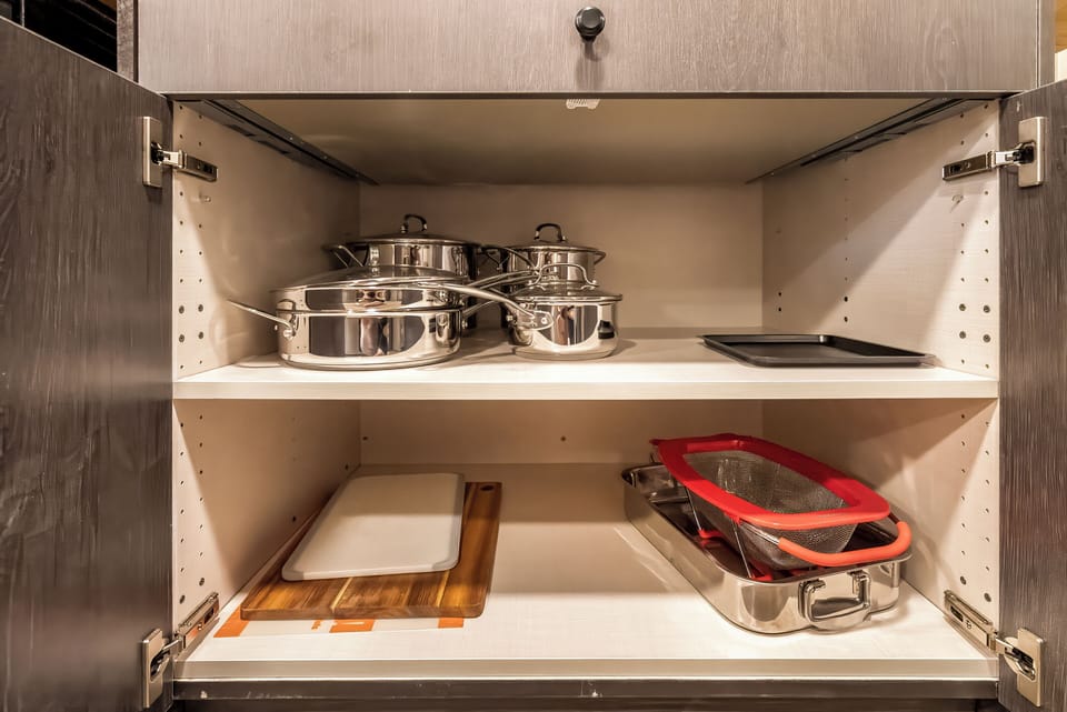Your culinary adventures await with premium cookware and cutting boards thoughtfully organized in easy-access kitchen storage.