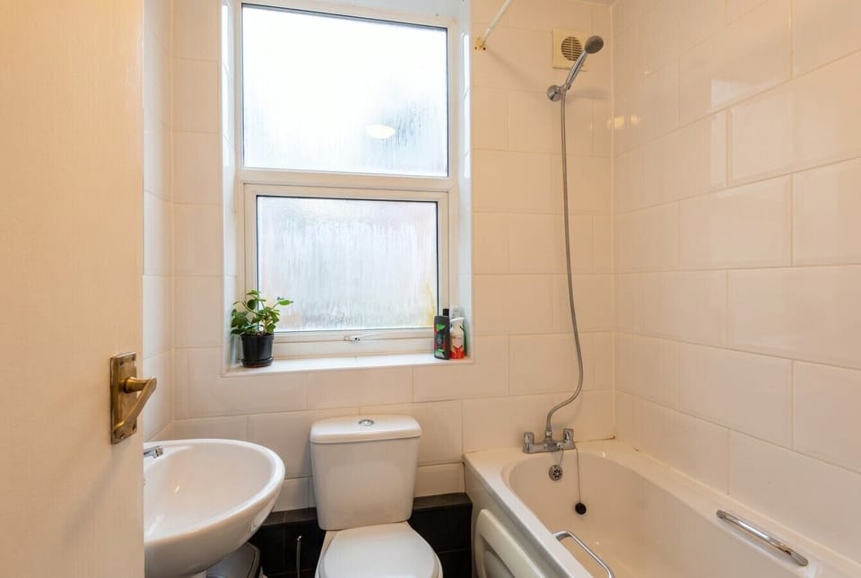 Clean shared bathroom with a full bath, overhead shower and natural light.