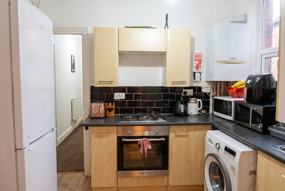 A fully equipped kitchen with oven, microwave, air fryer and washing machine.