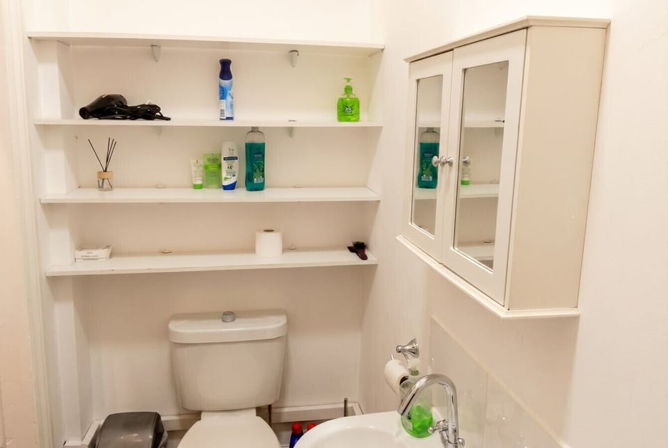 Bathroom shelving stocked with essentials including a hair dryer, hand soap, and extra toiletries.