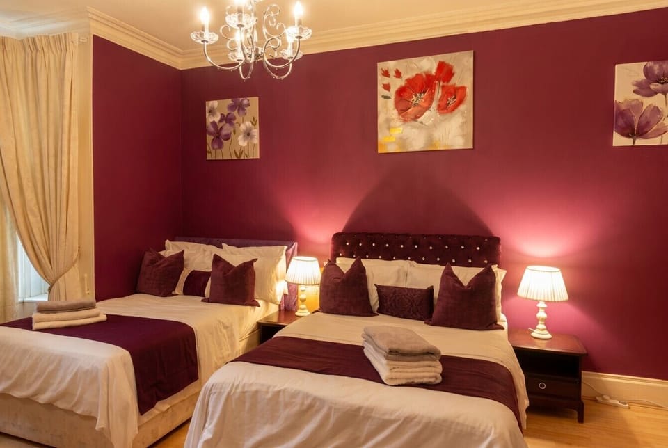 Warmly lit twin bedroom dressed in rich burgundy, where guests sink into plump pillows each night.