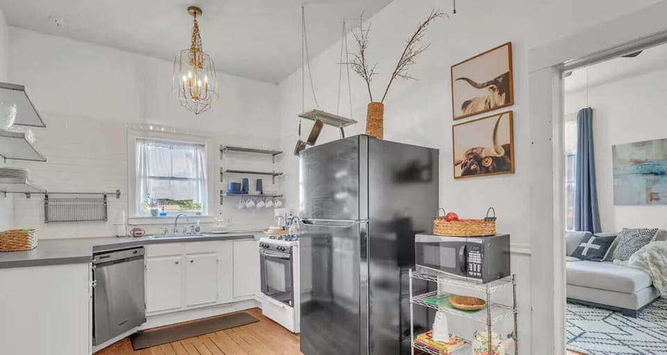 A bright kitchen anchored by a full-size fridge, gas range, and pantry shelving, opening directly to the living area.