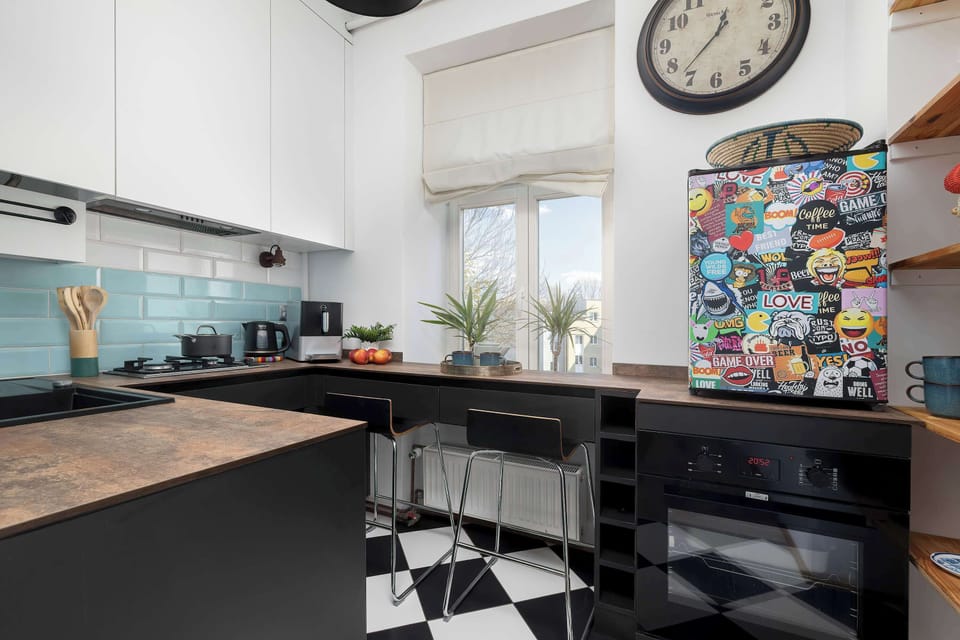 A functional kitchen with a window, beneath which a work surface has been installed, allowing for cooking in natural light. Numerous magnets adorn the refrigerator, giving the interior a relaxed, vacation-like atmosphere.