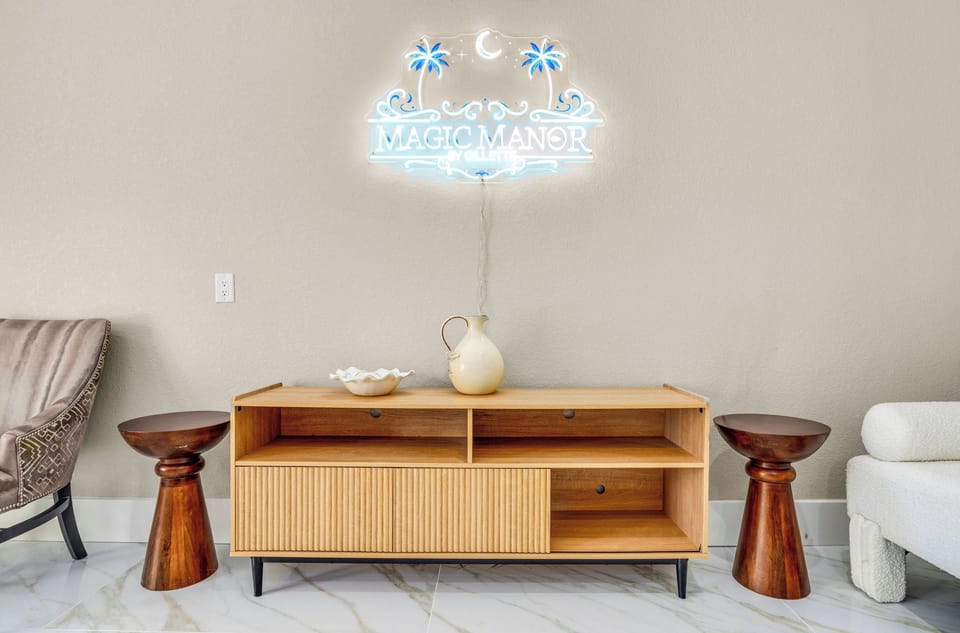 Relax in your stylish living space with handcrafted wooden furniture and a charming neon sign creating the perfect ambiance.