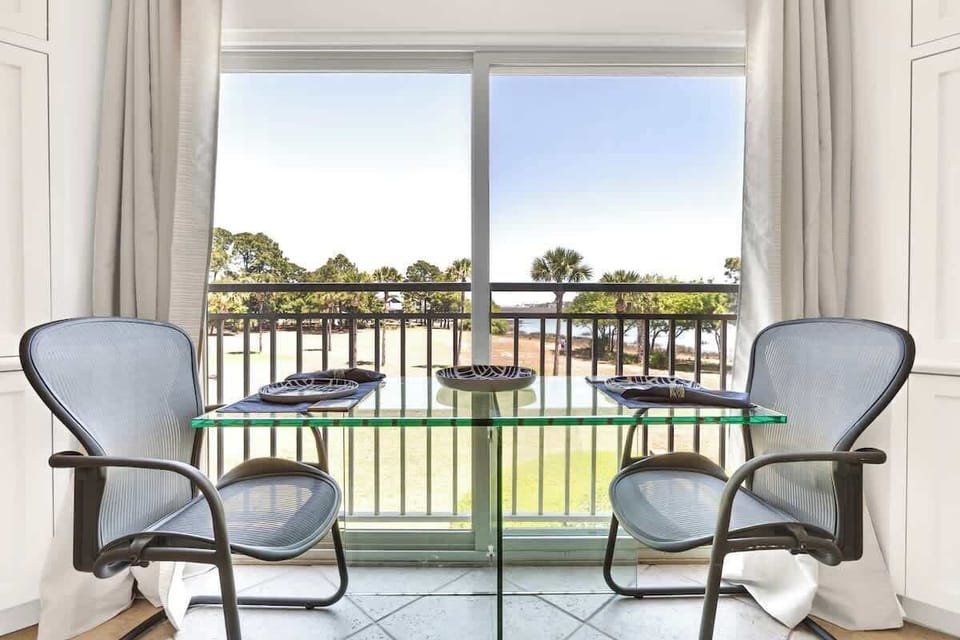 Enjoy intimate meals at your private glass dining table with stunning golf course views through floor-to-ceiling windows.