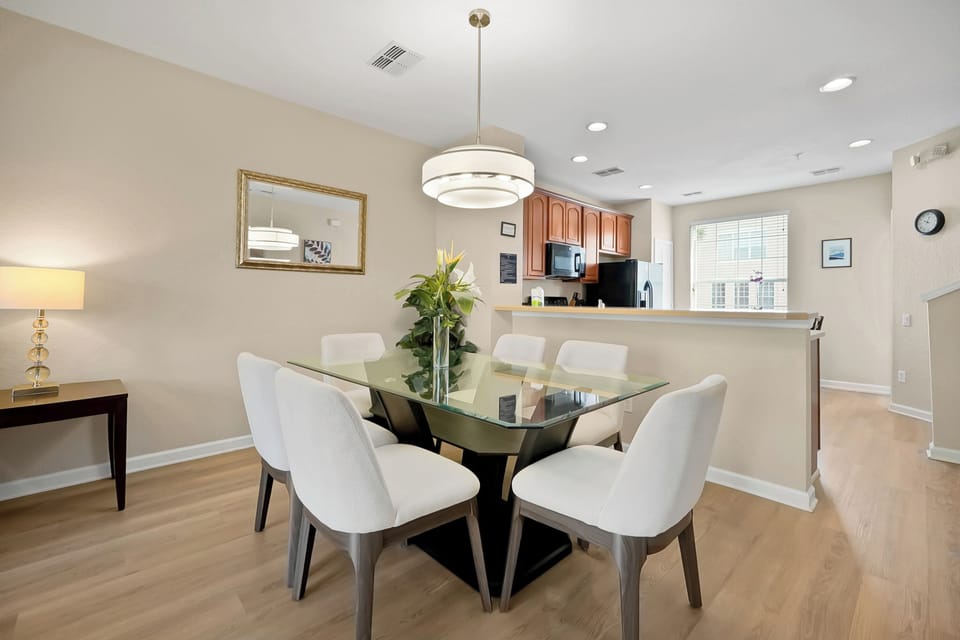 Gather around your elegant glass dining table for memorable meals, perfectly positioned between your modern kitchen and living space.