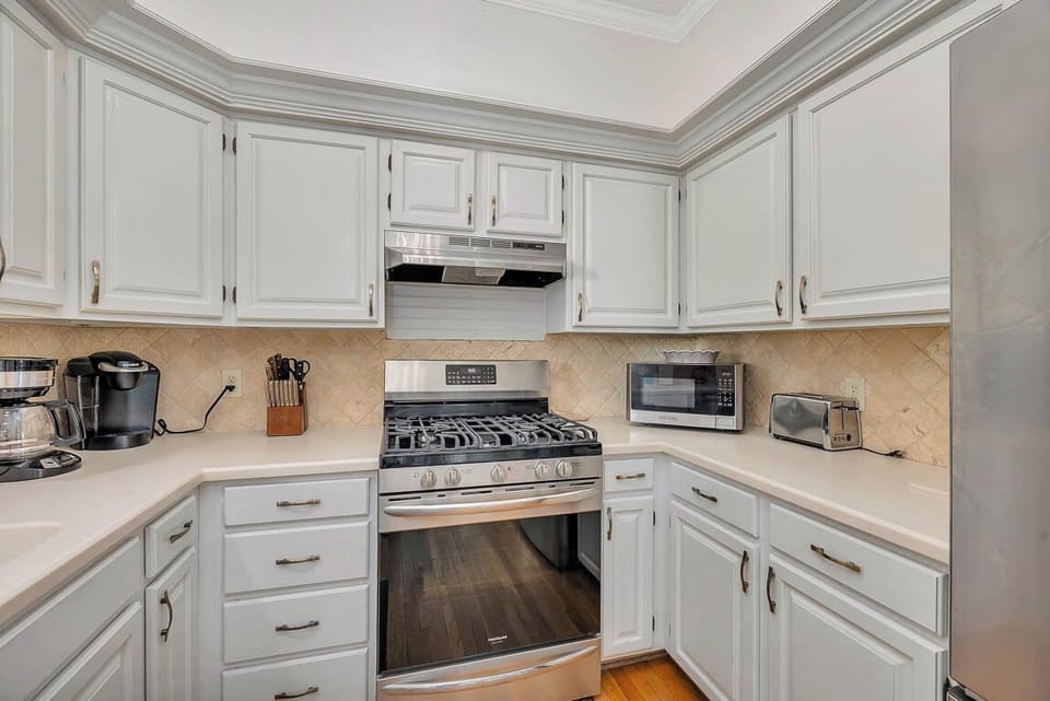 Whip up your favorite meals in this fully-equipped kitchen with modern appliances and elegant white cabinetry.