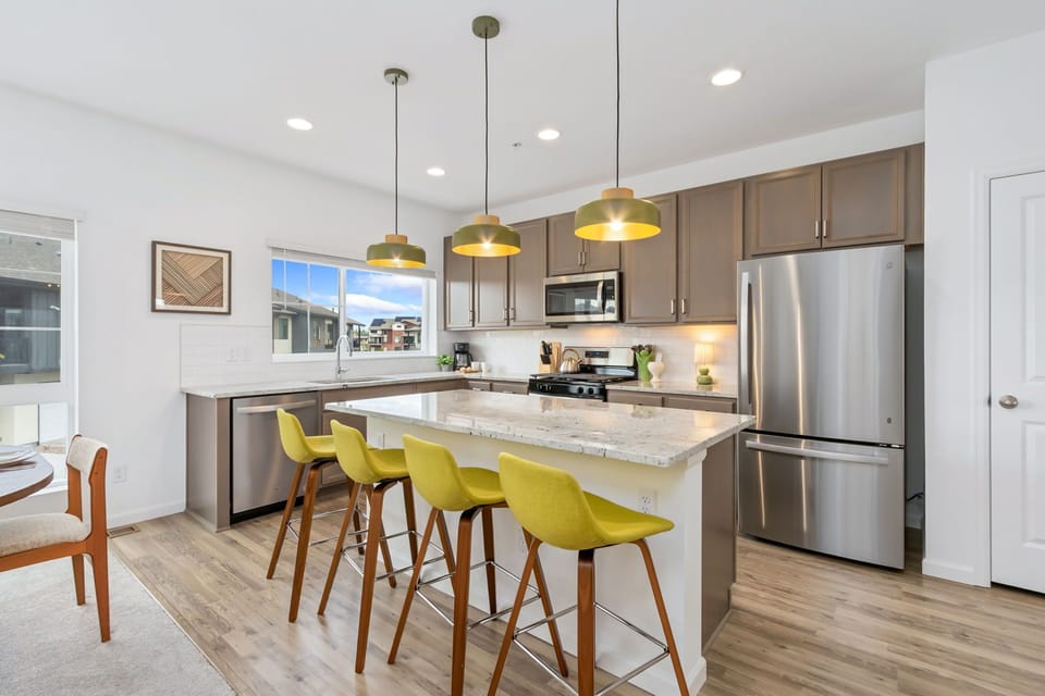 Your modern kitchen invites gathering around the bright island, featuring granite countertops, stainless appliances, and pendant lighting—perfect for cooking and entertaining together.