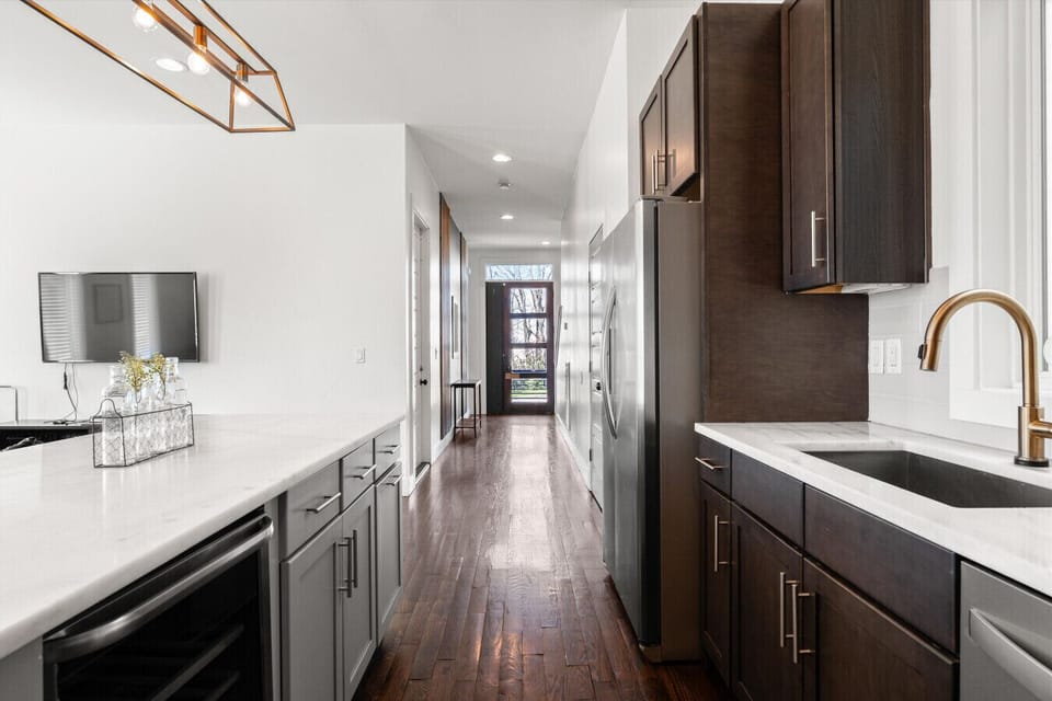 Home 1: Step inside and feel it instantly — warm wood accents, soaring ceilings, and a stunning sight line straight through to the kitchen.