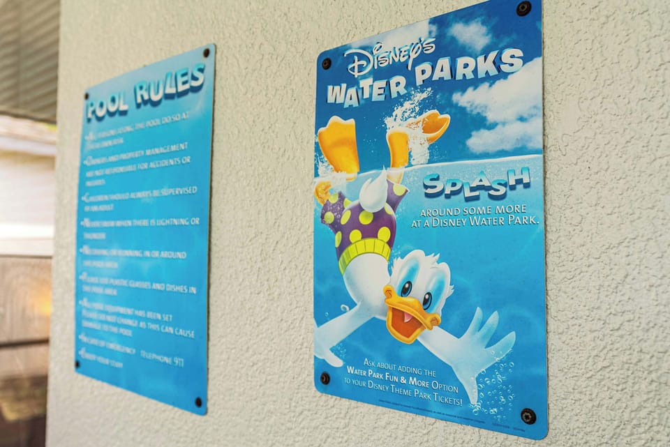 A colorful Disney water parks sign next to pool rules on a textured wall
