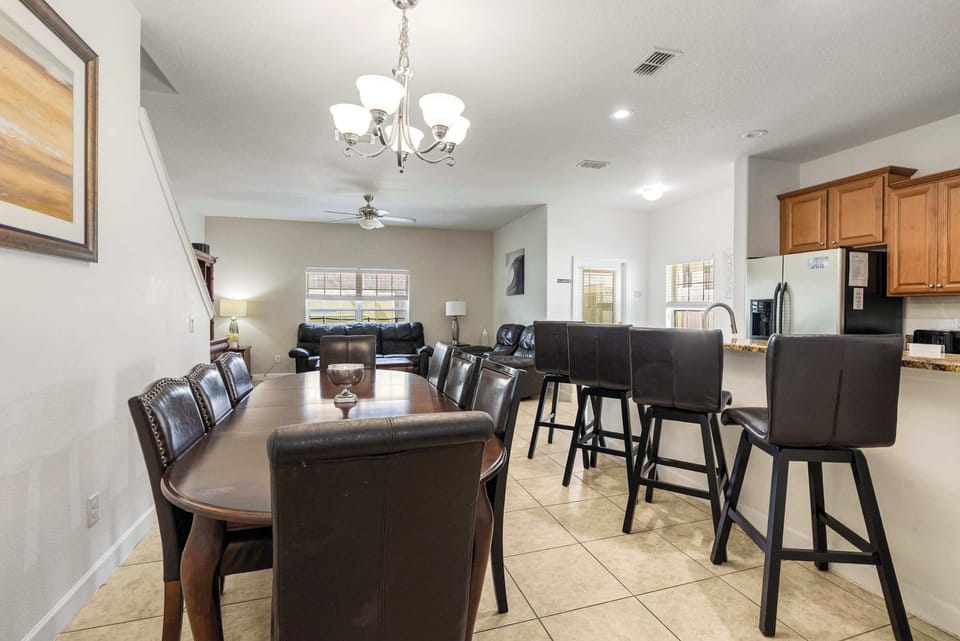 Open dining and kitchen area with leather seating and modern lighting.