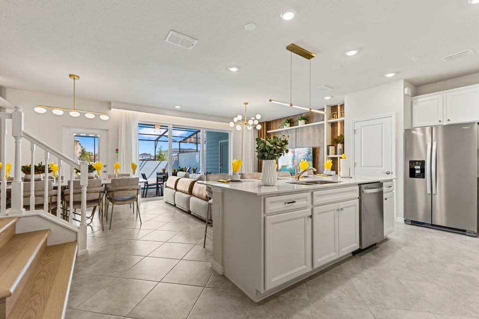 Bright open-concept kitchen and living area with a large island, stainless appliances, and ample dining-slide open the doors to the screened patio and private pool.