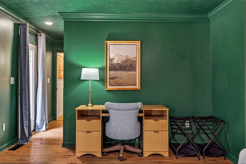 Stay productive without sacrificing comfort — the dedicated workspace features a classic wooden desk, warm lighting, and rich emerald green walls that make even a work session feel like a retreat.