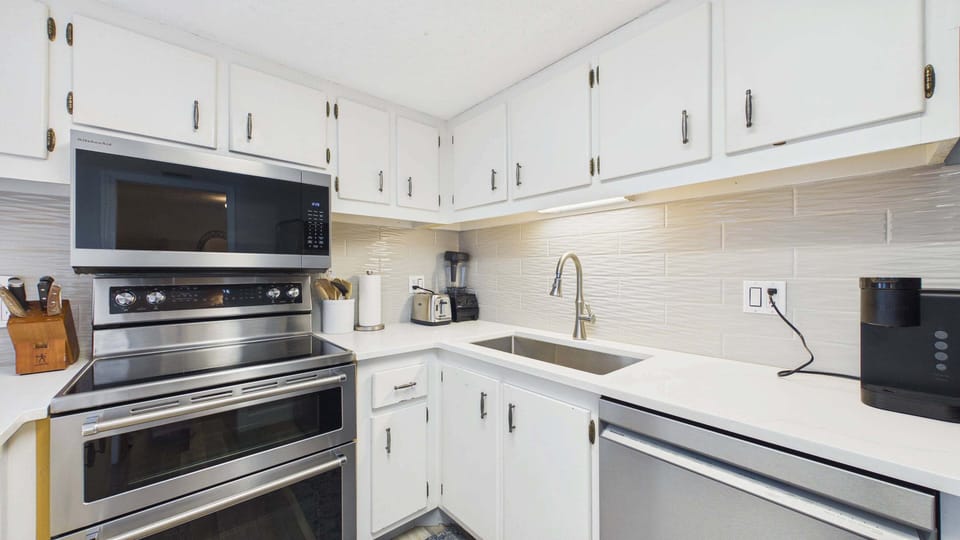 Modern appliances throughout kitchen including deep basin sink and coffee essentials
