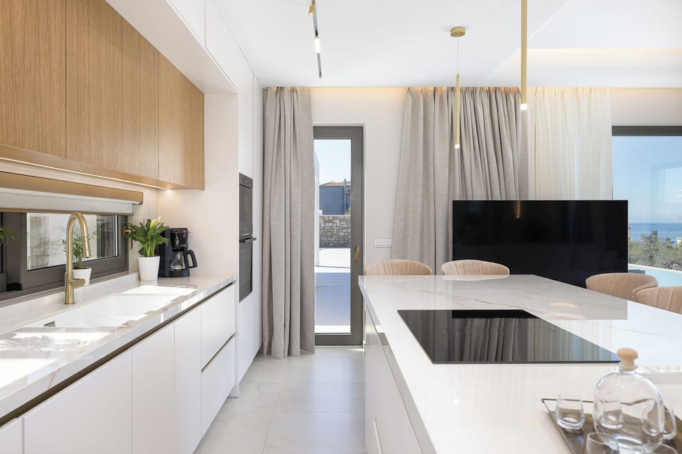 The fully equipped kitchen includes modern appliances and a spacious island with seven stools, while the dining area comfortably seats up to eight guests, making it ideal for shared meals and gatherings.