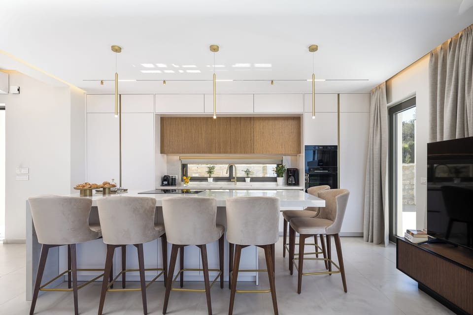 The fully equipped kitchen includes modern appliances and a spacious island with seven stools, while the dining area comfortably seats up to eight guests, making it ideal for shared meals and gatherings.