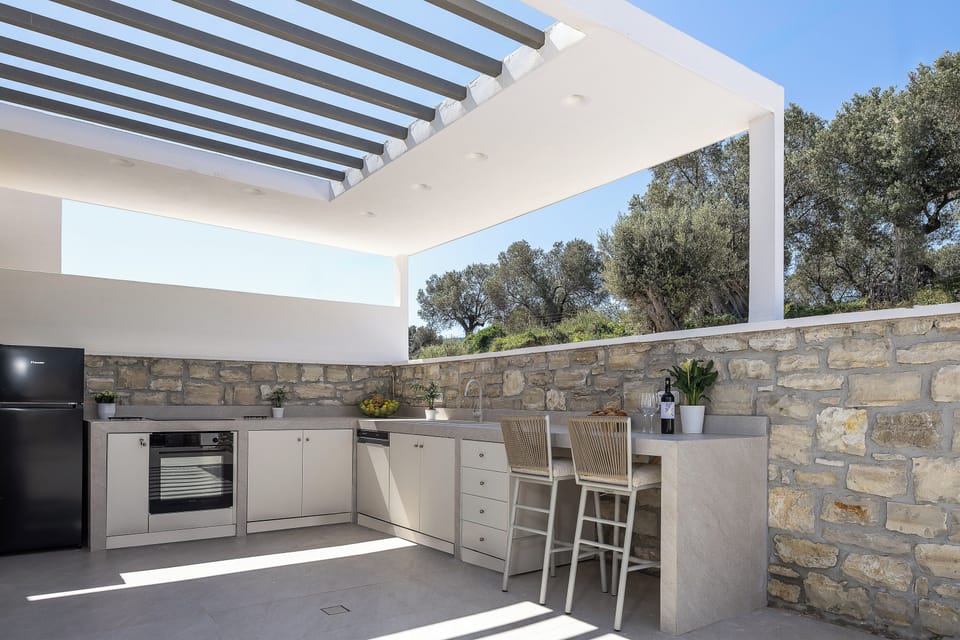Outdoor kitchen with an electric BBQ grill, an oven, a stove top, a refrigerator, a dishwasher, a sink, and ample counter and storage space.