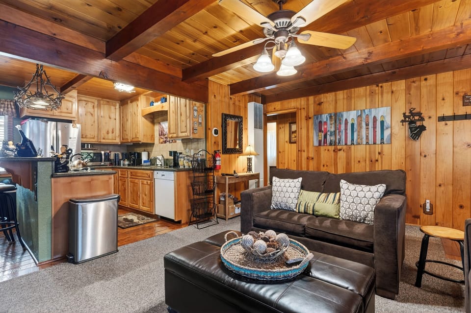 A warm, wood-lined living space with a fireplace and open layout sets the tone for a classic cabin stay.
