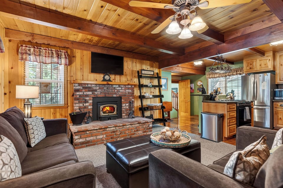 A warm, wood-lined living space with a fireplace and open layout sets the tone for a classic cabin stay.