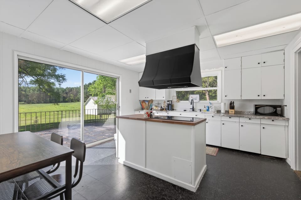 Sunny kitchen with large windows and outdoor views.