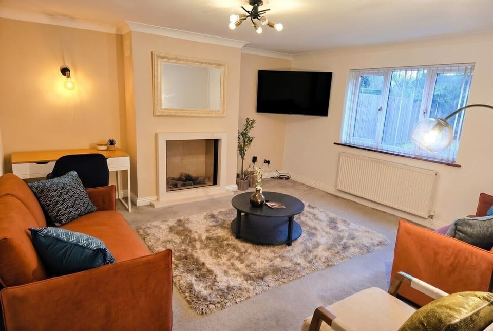 Welcoming lounge with fireplace, smart TV, velvet sofas, and a workspace.
