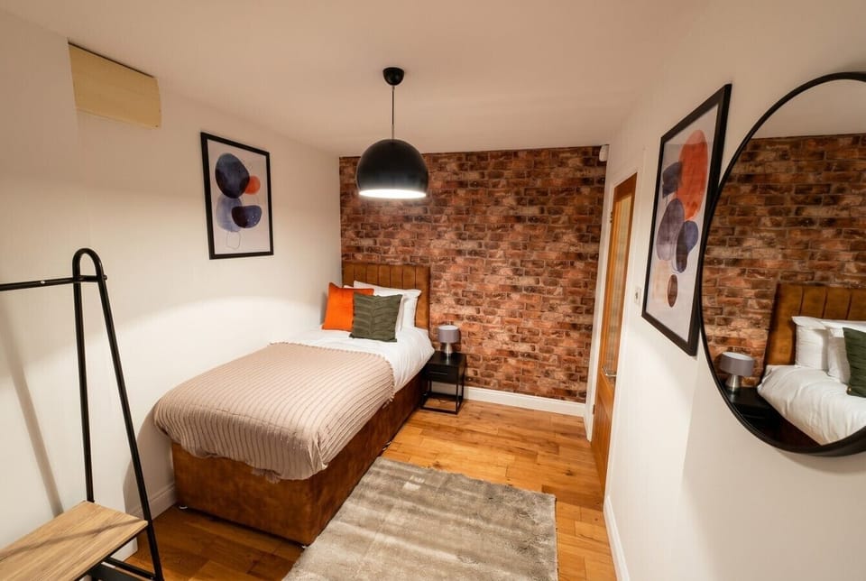 Single bedroom with exposed brick wall and warm pendant lighting.