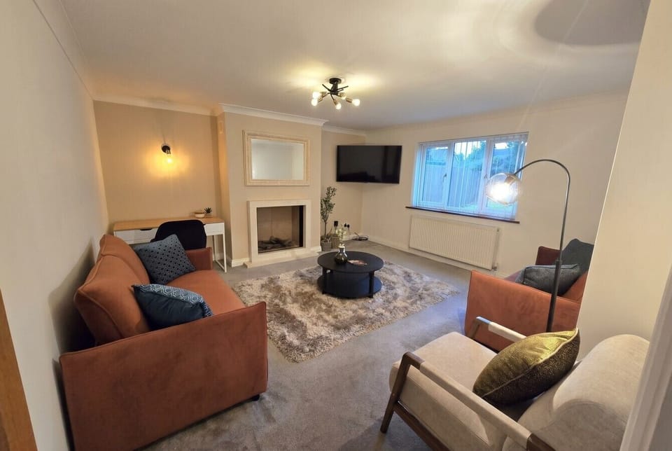 Wide-angle view of the warm lounge with fireplace and armchairs.