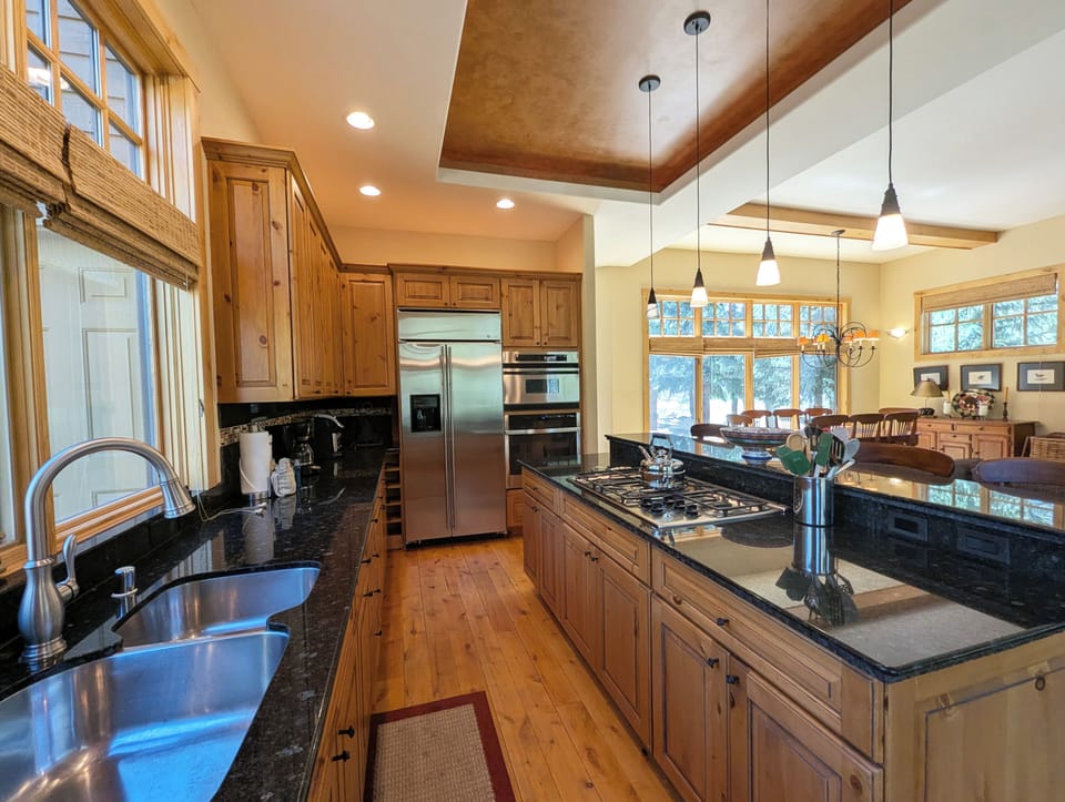 This beautiful kitchen invites you to create memorable meals with granite counters, stainless appliances, and warm wood cabinetry throughout your stay.