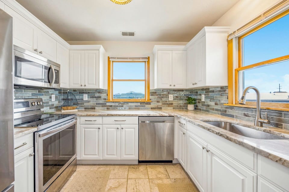 Your fully equipped kitchen features granite counters, stainless appliances, and charming tile backsplash—perfect for preparing meals while enjoying scenic views.
