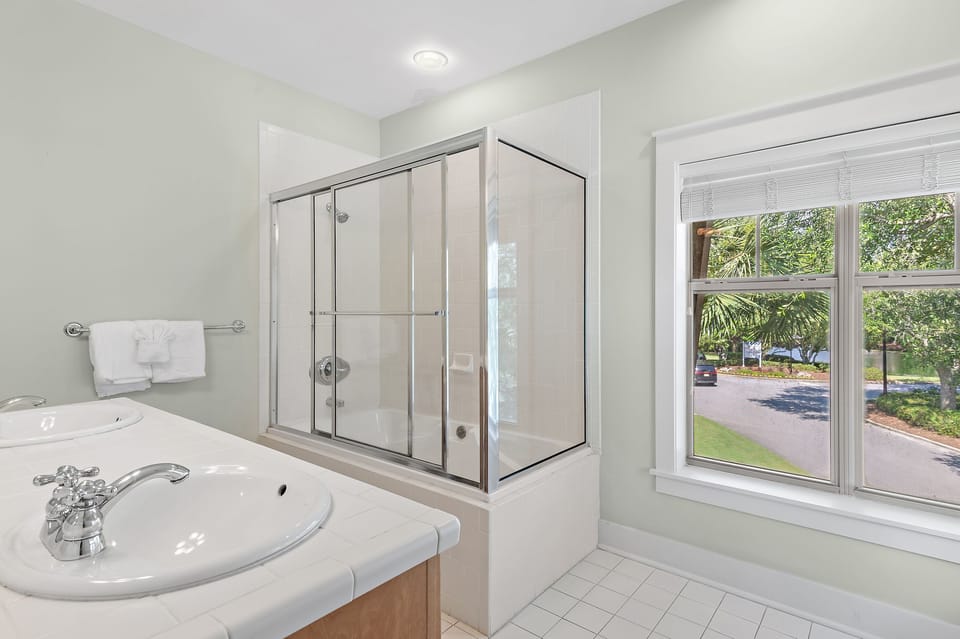 Second full bathroom with dual vanities, shower/tub combo, and plenty of natural light