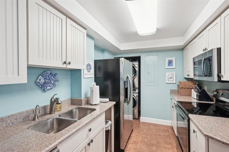 Your fully-equipped kitchen invites effortless meal prep with granite counters, double sinks, stainless appliances, and cheerful coastal accents that set a relaxed, beachy mood.