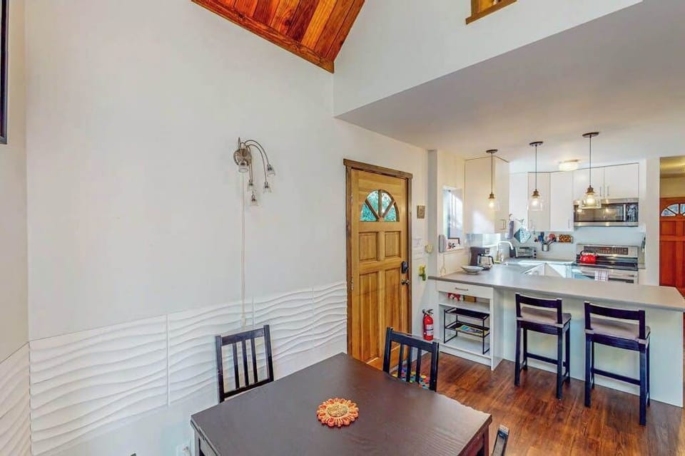 From the dining nook, a stained-glass front door winks beside your open kitchen — pendant lights set the mood for evening meals.