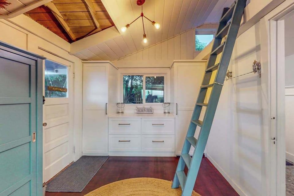 Discover your cottage's adventurous side — a ladder leads up to a loft sleeping nook, with built-in drawers and twinkling string lights setting the mood below.