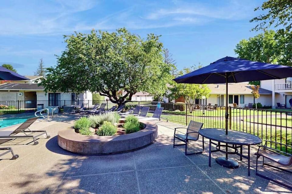 Gather around the shaded courtyard at your Napa resort pool — umbrella tables and a signature raised planter set the scene