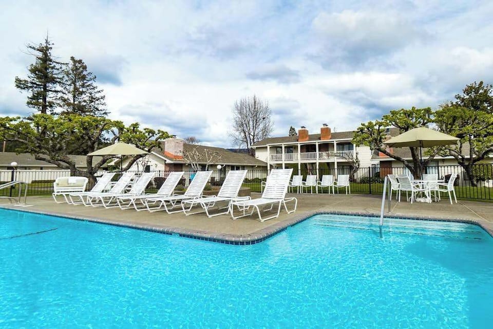 Lounge poolside under Napa Valley sunshine at your resort pool — chaise lounges and shaded seating await after a day of wine tasting