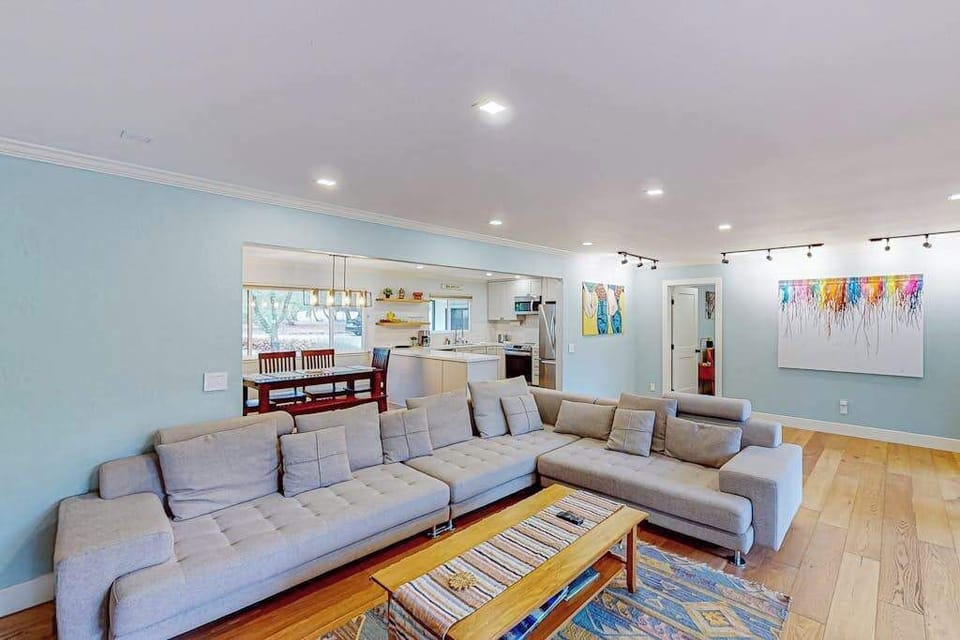 Bright, airy, and art-filled — your open-concept living space flows seamlessly into the kitchen, with track lighting highlighting curated artwork perfect for a wine country vibe.