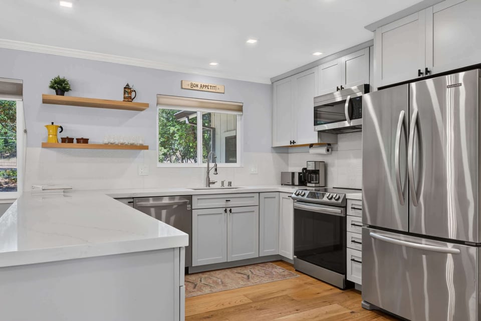 Cook with ease in the chef's kitchen — quartz counters, stainless appliances, and a cheerful 'Bon Appétit' nod above the sink.