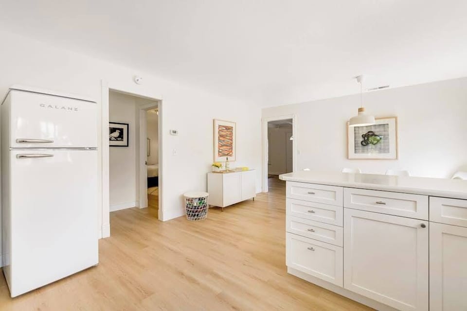 Discover retro-chic charm in your farmhouse kitchen — a vintage-style fridge, sleek white cabinetry, and ample counter space for crafting Sonoma-inspired meals.