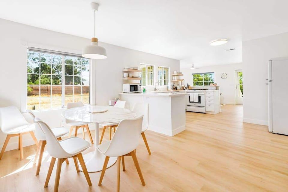 Gather your group around the modern round dining table, then step into the all-white chef's kitchen — bright, airy, and ready for your Healdsburg farmers market haul.