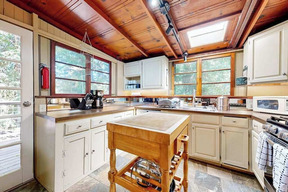 Cook like a local in your fully equipped kitchen — a butcher-block island, ample counter space, and forest views through every window.