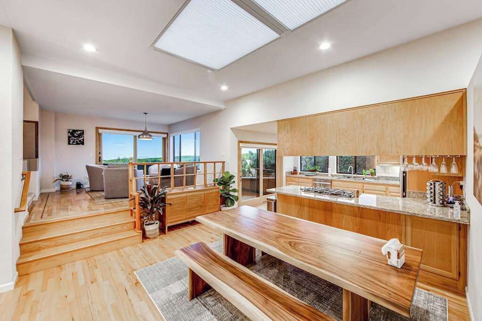 Cook like a local in your skylit gourmet kitchen — gas stove, warm wood cabinetry, and a rustic live-edge dining table steps away