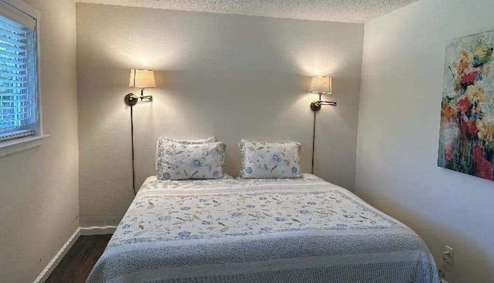 Wind down in your intimate king bedroom — swing-arm reading lamps and soft floral accents create the perfect end to a Kenwood tasting trail day.