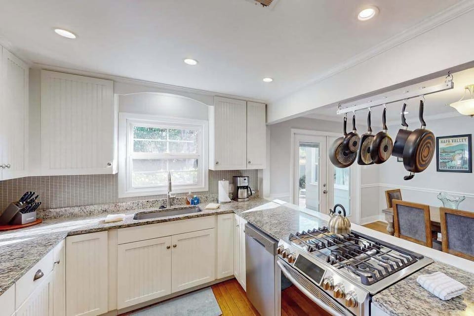 Everything you need for Sonoma farmers market feasts — gas range, deep farmhouse-style sink, coffee maker, and granite counters stocked with quality cookware