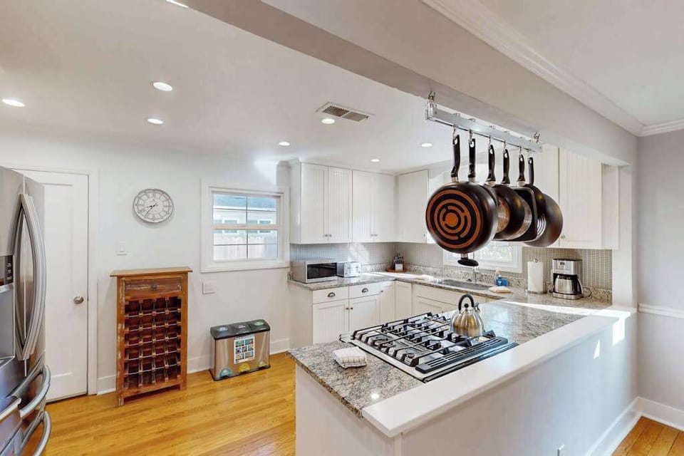 Cook like a local in your chef-ready kitchen — gas range, granite countertops, a wooden wine rack, and professional-grade hanging pans at your fingertips