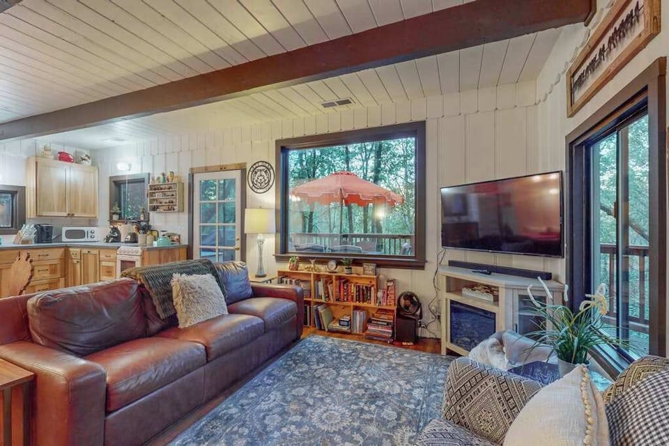 Catch a movie on your flat-screen TV while the treetops sway beyond the windows — this open-plan living space connects seamlessly to your fully equipped kitchen.