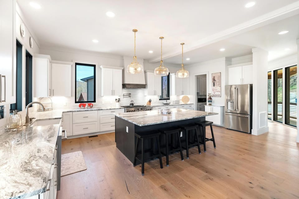 Cook gourmet meals in this bright, spacious kitchen featuring granite countertops, stainless steel appliances, and elegant pendant lighting over the large island.