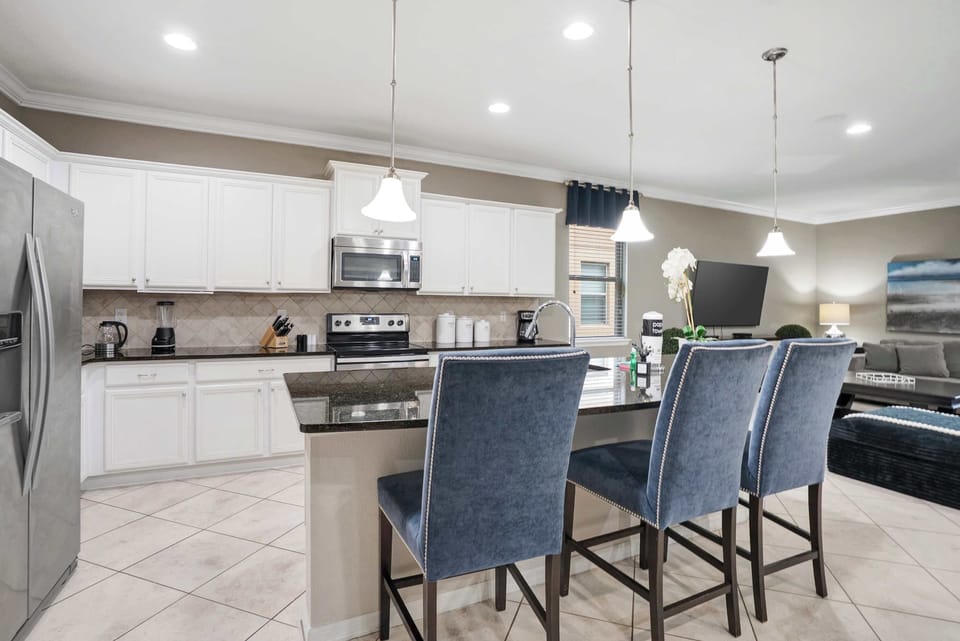 Modern kitchen with white cabinetry and a granite island featuring comfortable seating.