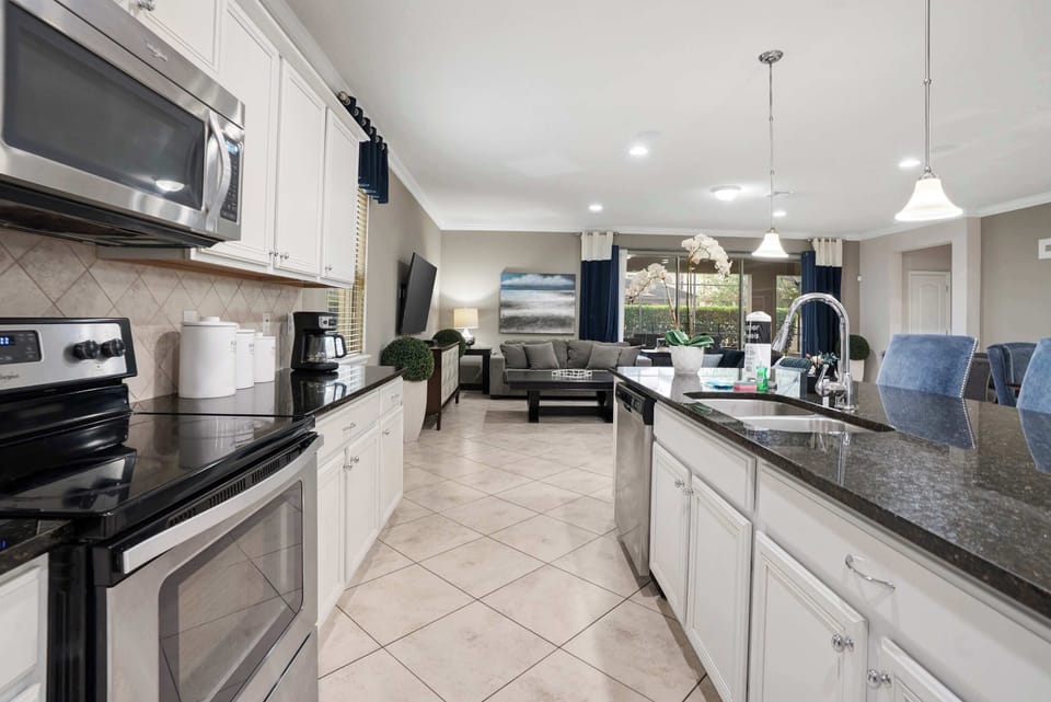 Modern kitchen with stainless steel appliances and a spacious island overlooking the living area.