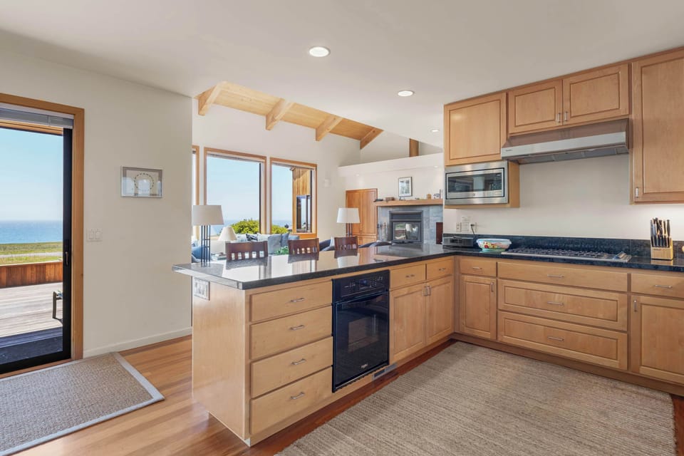 Cooking corner opens straight to the deck slider and the ocean view — your morning eggs, your evening pinot, all within steps of the bluff.