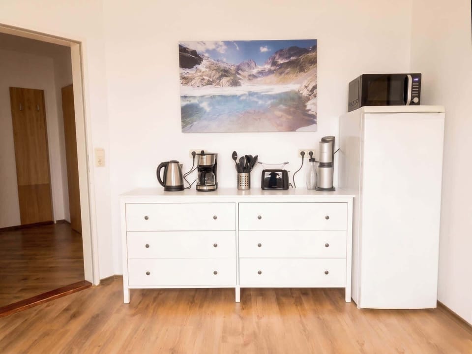 Verschiedene Küchengeräte wie Kaffeemaschine, Wasserkocher, Mikrowelle & Kühlschrank